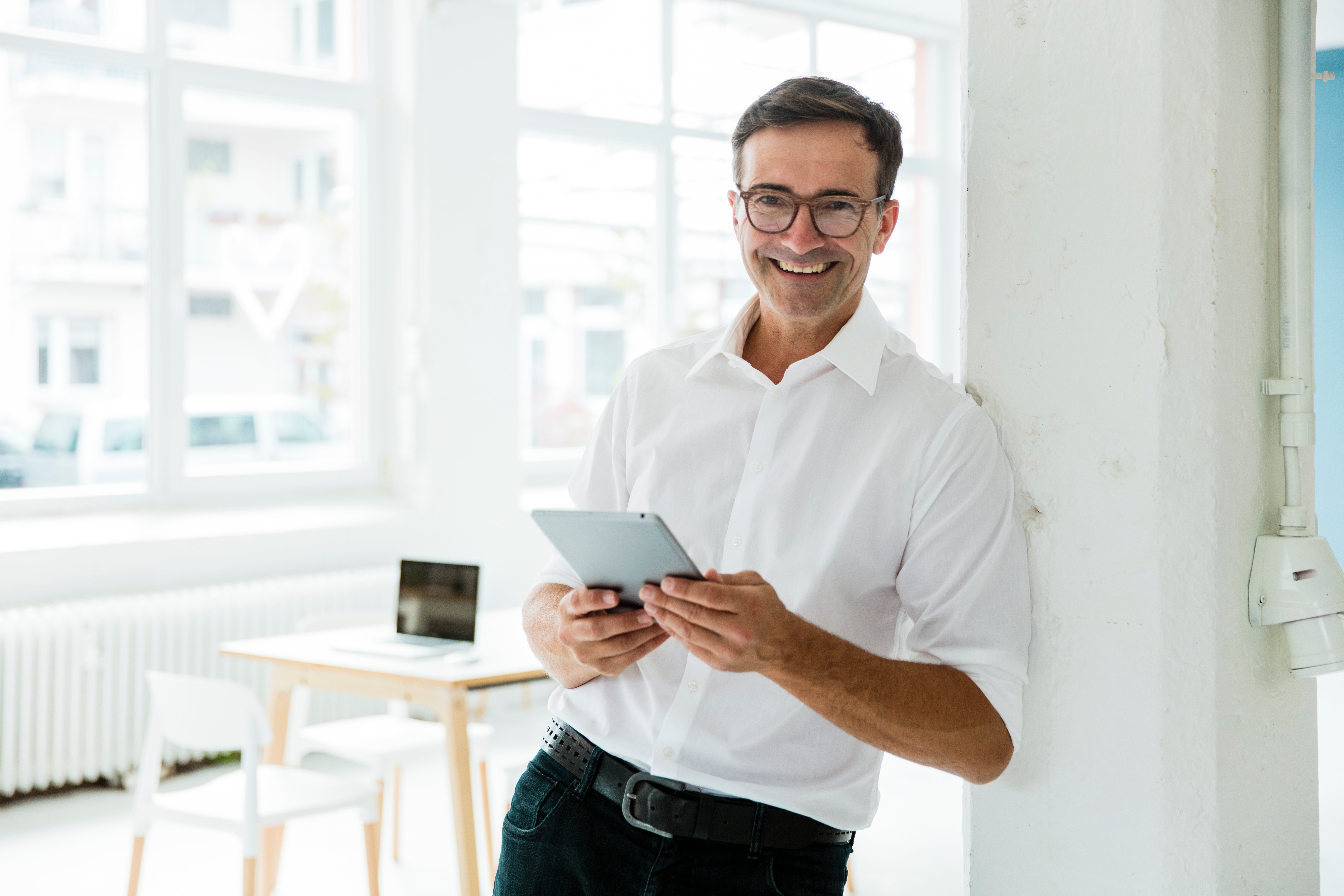 man smiling holding tablet and looking at camera